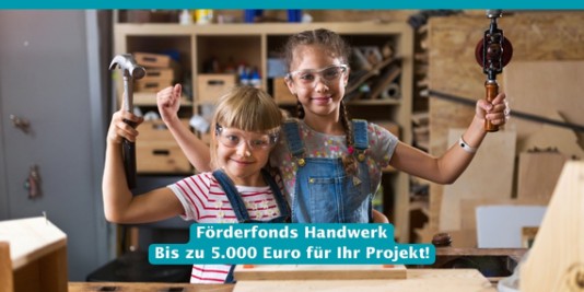 Zwei Mädchen mit Schutzbrillen und Werkzeugen in der Hand schauen glücklich und stolz in die Kamera.