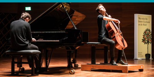 Zwei Menschen musizieren auf der Bühne an einem Flügel und einem Cello.